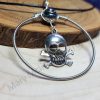 Guitar string wound into a circular pendant with a skull and crossbones embellishment