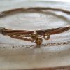 twisted guitar string bangle with pegs still intact, wire wrapped in gold